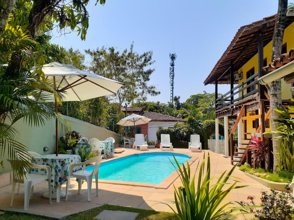 una piscina con sillas y una mesa junto a una casa en Pousada Arraial Lua Crescente, en Arraial d'Ajuda