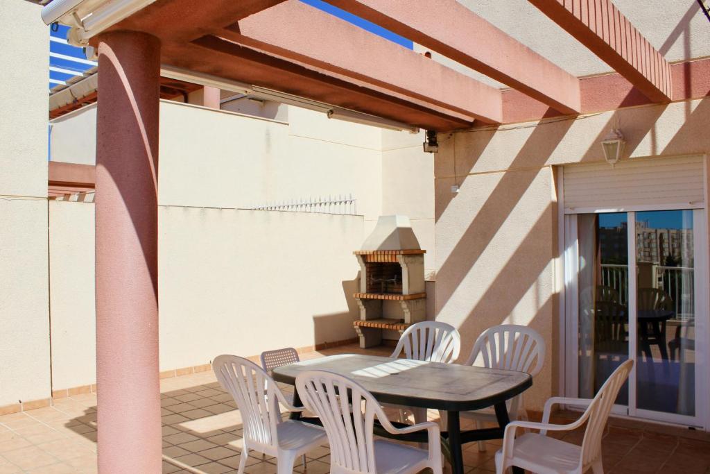 un patio avec une table, des chaises et un grill dans l'établissement Espectacular Ático con Parking y Terraza con BBQ, à Salobreña