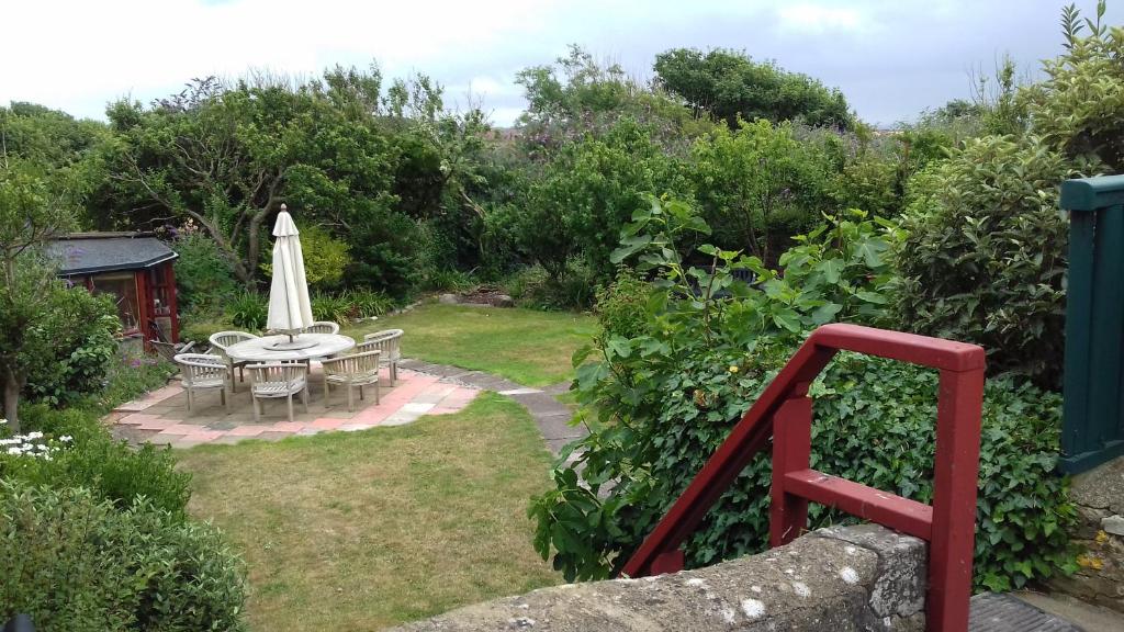 um pátio com uma mesa e um guarda-sol num jardim em Delfryn Guest Suite em Haverfordwest