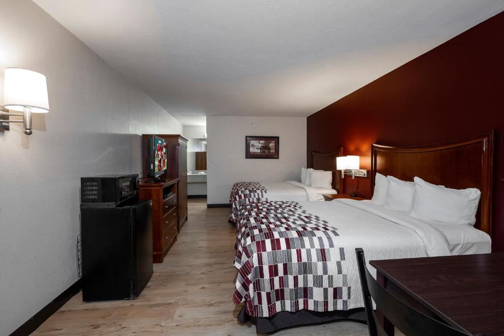um quarto de hotel com duas camas e uma mesa em Red Roof Inn Dothan em Dothan