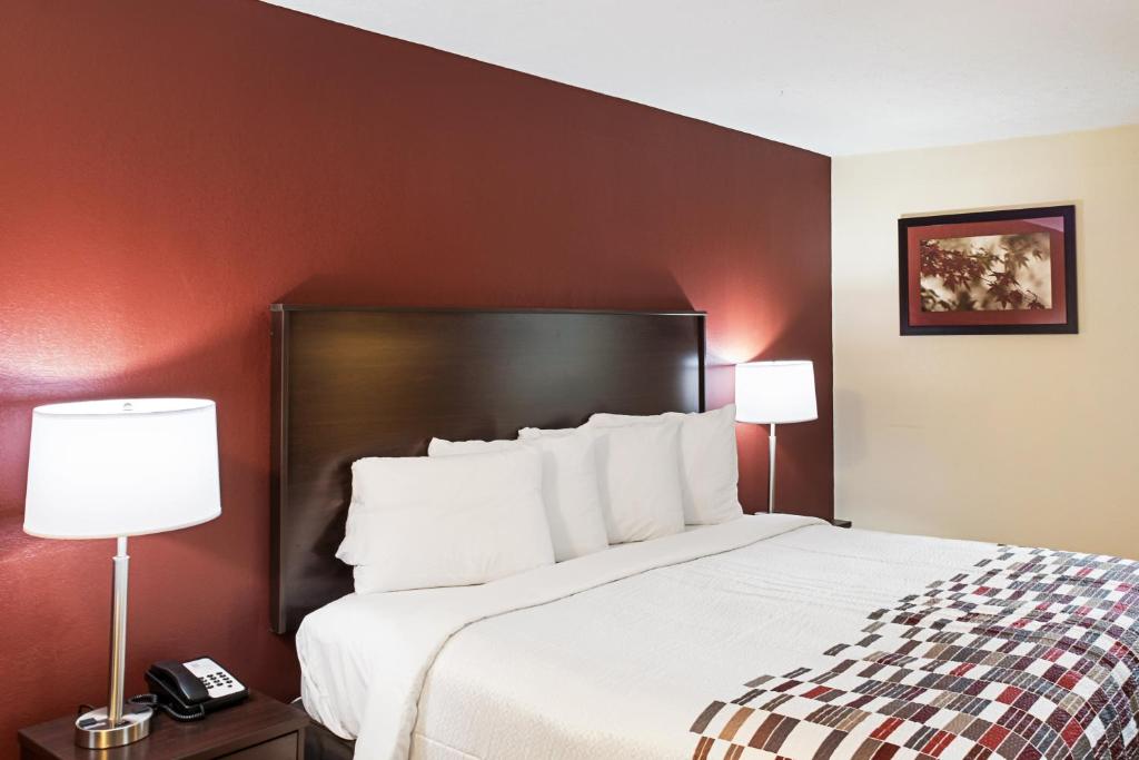 una camera d'albergo con un grande letto con due lampade di Red Roof Inn Indianapolis East a Indianapolis