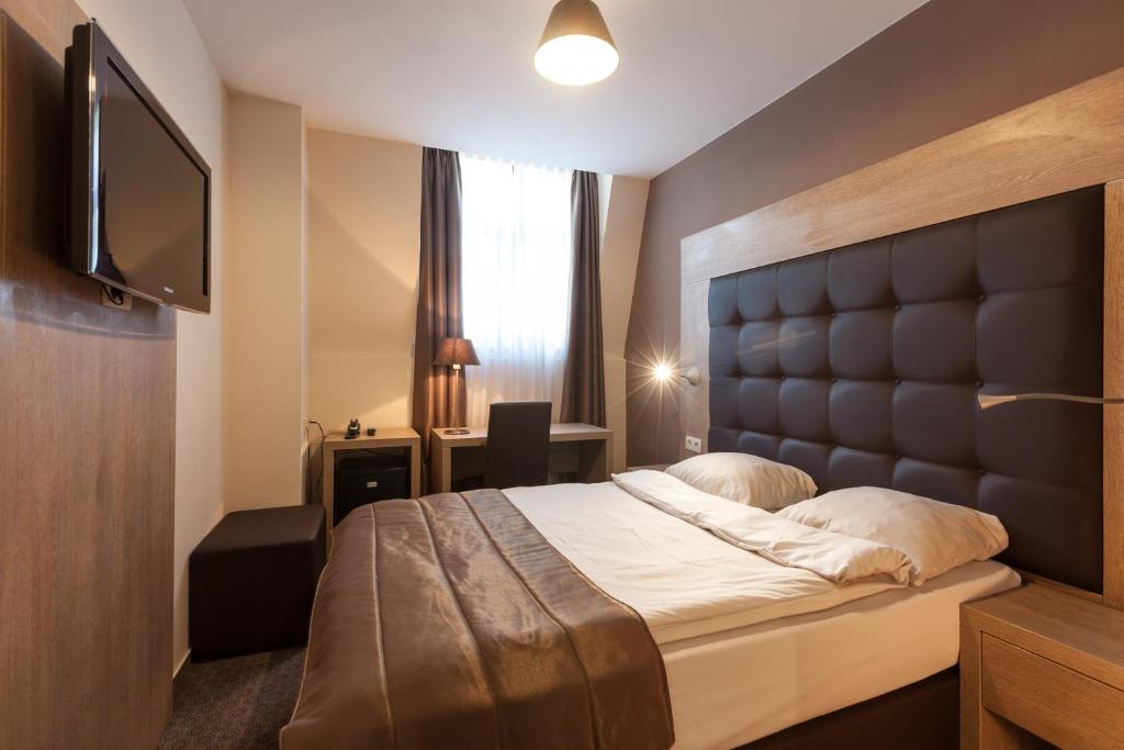 a bedroom with a bed and a flat screen tv at Hotel Villa Royale in Brussels