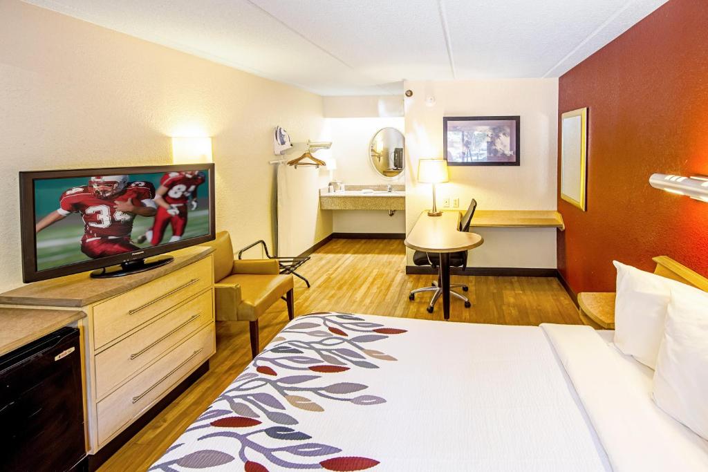 a hotel room with a bed and a flat screen tv at Red Roof Inn Erie – I-90 in Erie