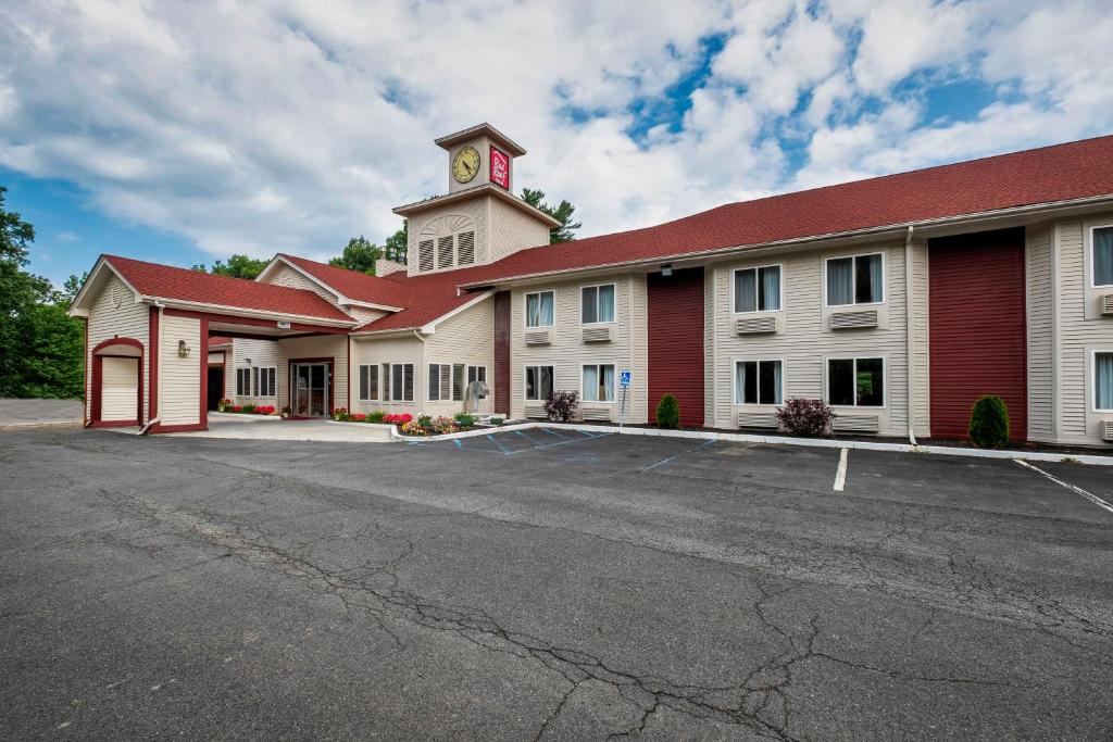 un edificio con una torre de reloj con aparcamiento en Red Roof Inn Clifton Park, en Clifton Park