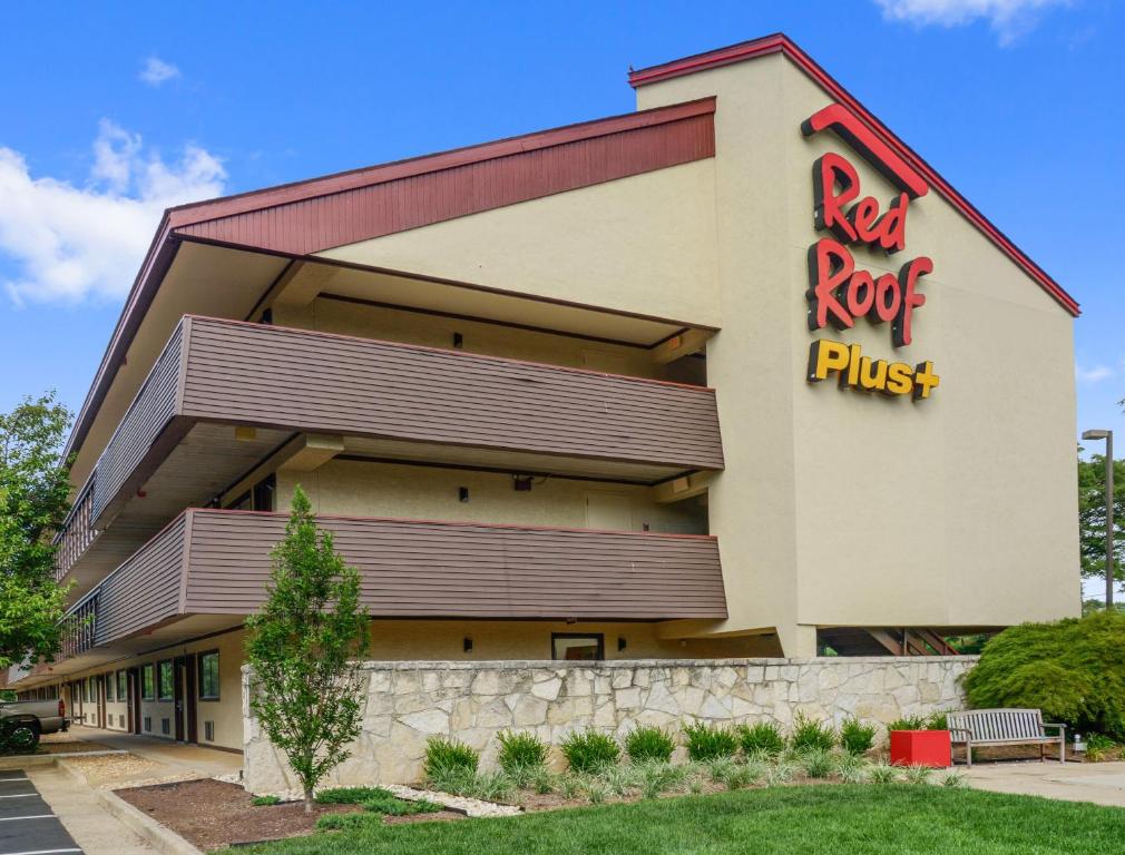 Red Roof Inn PLUS+ Washington DC - Manassas في ماناساس: صخرة حمراء بالإضافة إلى مبنى به صخرة حمراء بالإضافة إلى علامة