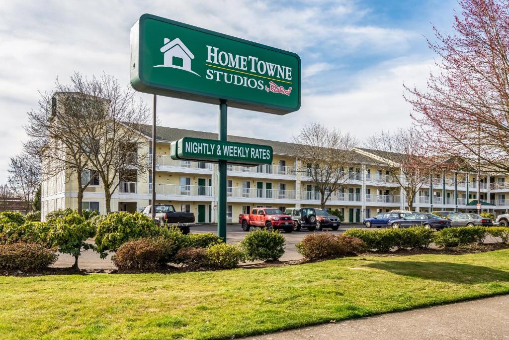 a sign in front of a hotel with a building at HomeTowne Studios by Red Roof Eugene - Springfield in Springfield