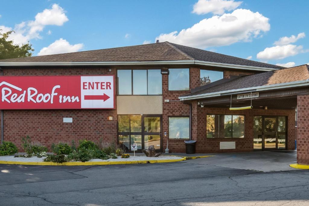 a red rock motel building with a red roof at Red Roof Inn Rochester - Airport in Rochester