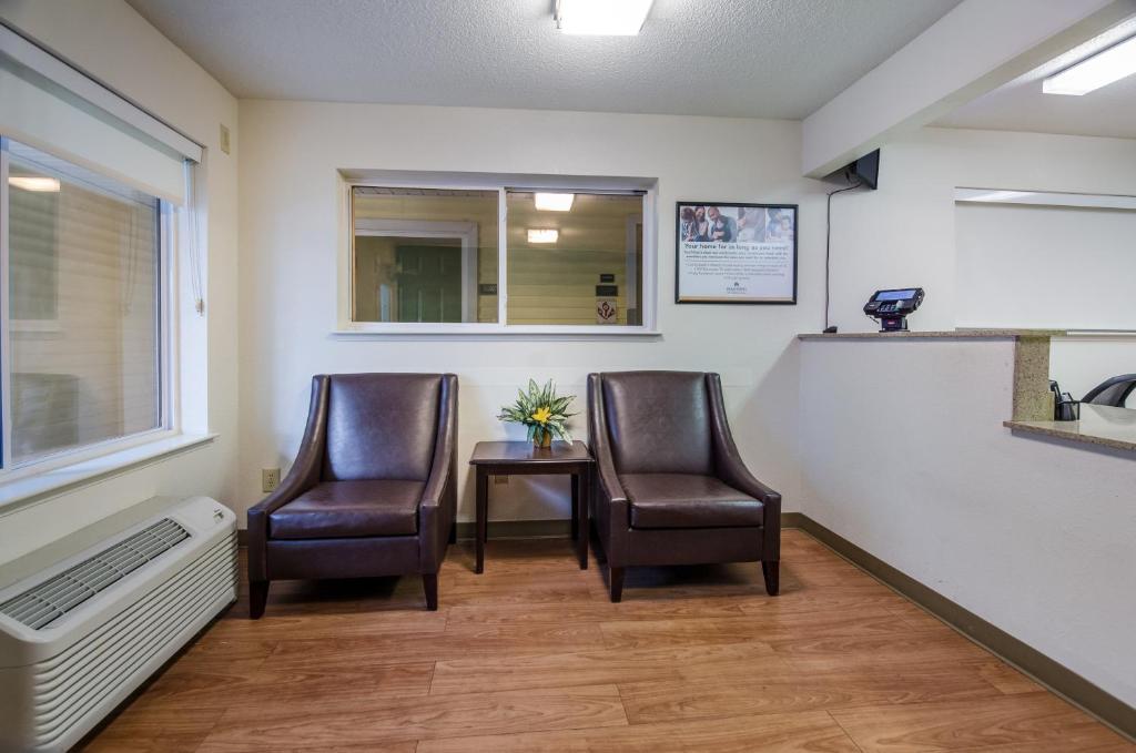 a waiting room with two chairs and a table at Suburban Studios Winston Salem-University Parkway in Winston-Salem