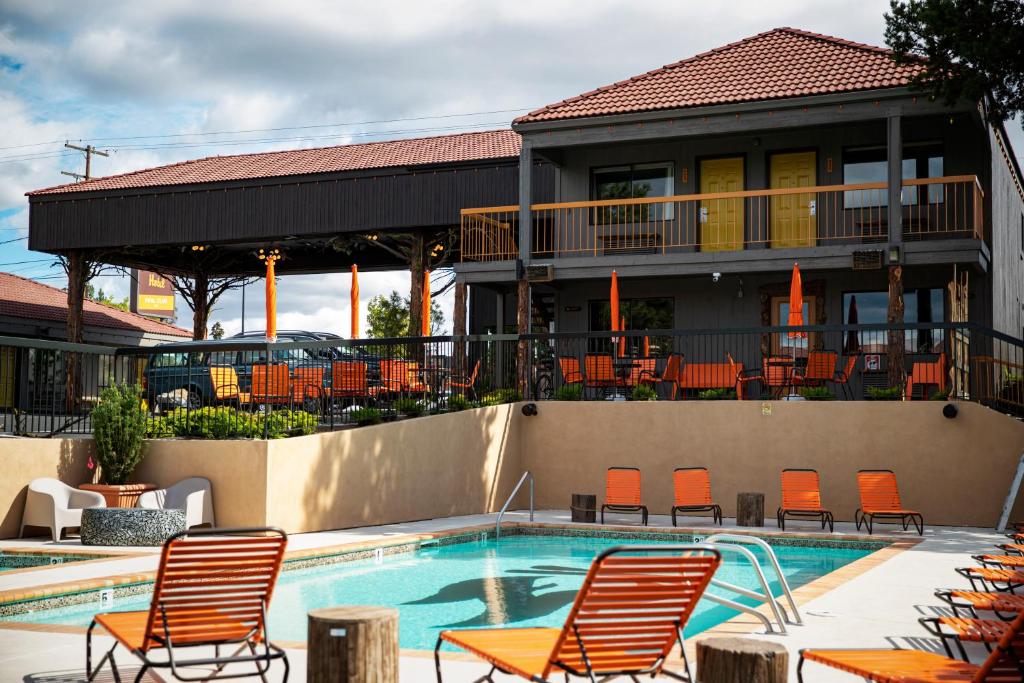 a swimming pool with orange chairs and a building at Campfire Hotel in Bend