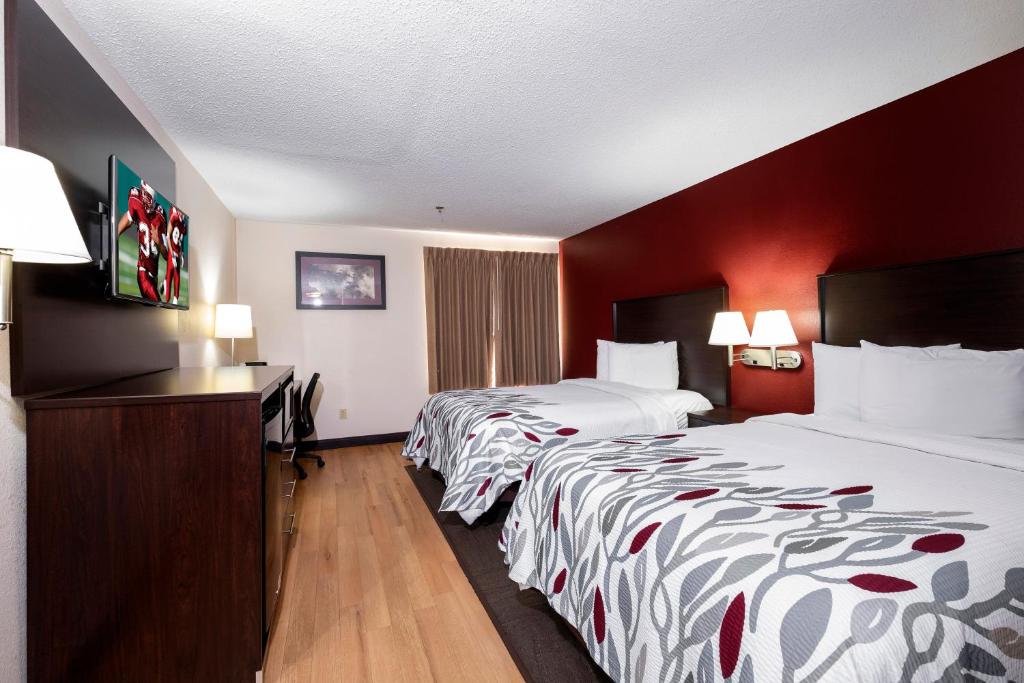 2 letti in una camera d'albergo con pareti rosse di Red Roof Inn Knoxville Central – Papermill Road a Knoxville