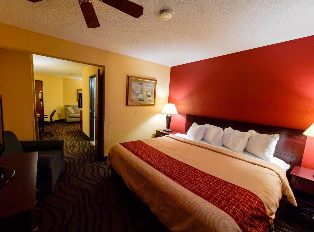 a hotel room with a large bed with a red wall at Baymont Inn & Suites by Wyndham Lincoln NE in Lincoln
