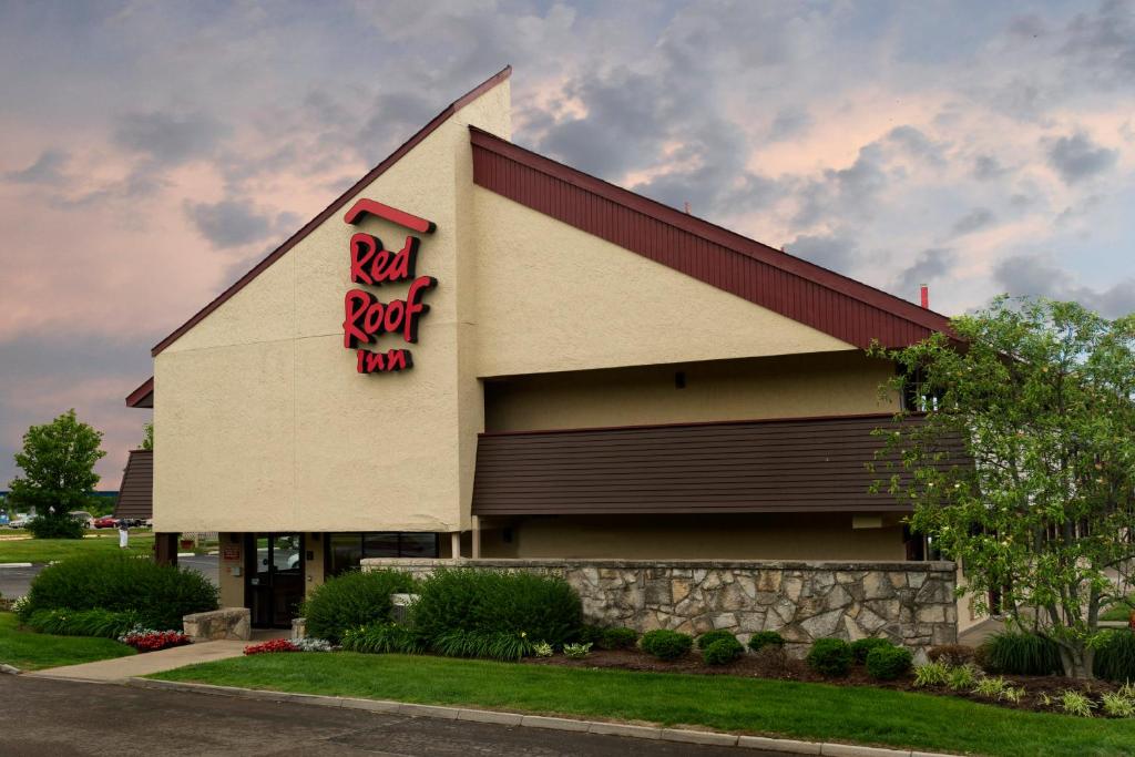 una señal roja de la posada en el lateral de un edificio en Red Roof Inn Dayton North Airport en Dayton