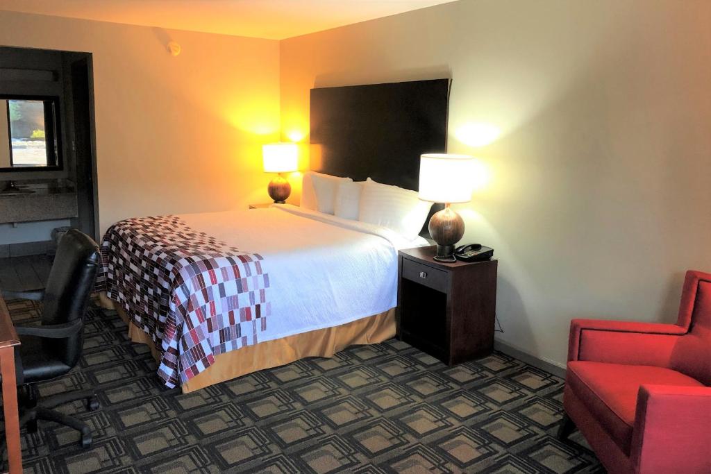 グリフィンにあるRed Roof Inn Griffinのベッドと赤い椅子が備わるホテルルームです。