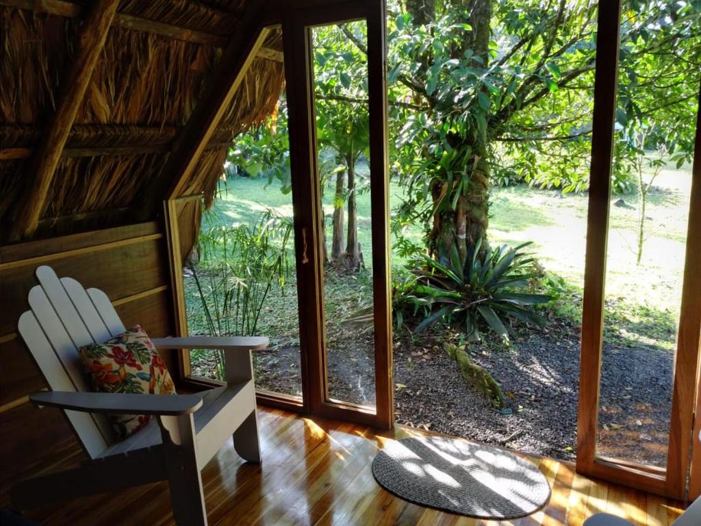 um quarto com uma cadeira branca e uma janela em Poponé Farm & Lodge em Guápiles