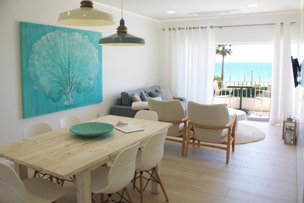 een woonkamer met een tafel en stoelen en de oceaan bij Front Sea Apartment in Quarteira