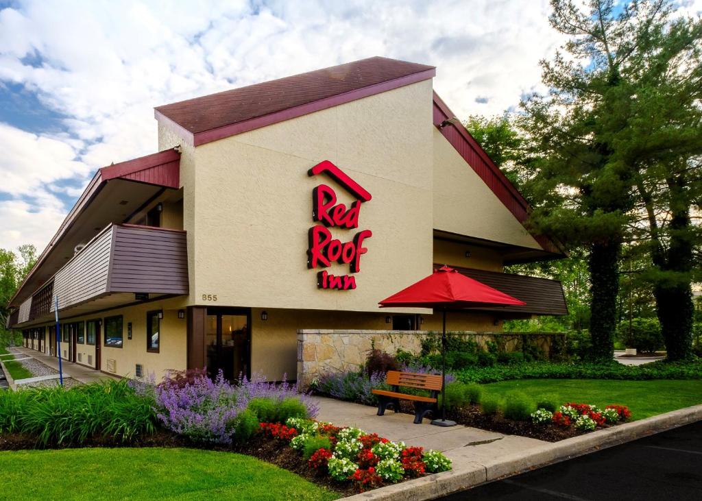 un bâtiment d'auberge au toit rouge avec un panneau sur celui-ci dans l'établissement Red Roof Inn Parsippany, à Parsippany