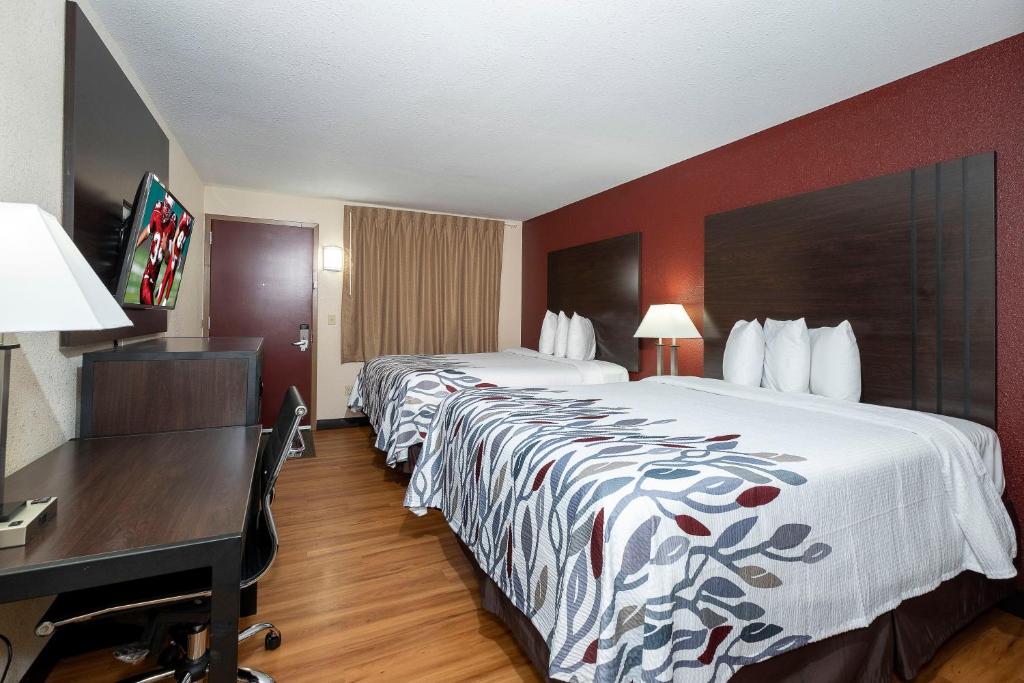 a hotel room with two beds and a desk at Red Roof Inn Freehold in Freehold