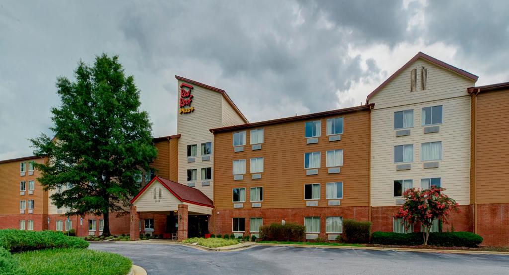 ローリーにあるRed Roof Inn PLUS Raleigh Downtown NCSU Conv Centerの木が目の前に建つホテルの建物