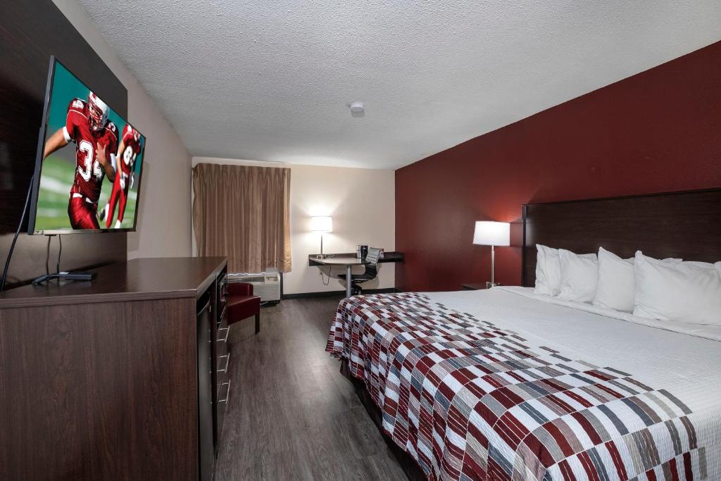 a hotel room with a bed and a flat screen tv at Red Roof Inn Prattville in Prattville