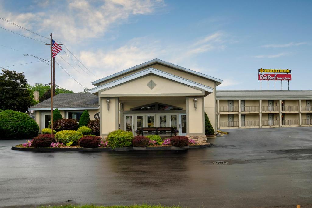 a hotel with an american flag in a parking lot at Red Roof Inn and Suites Herkimer in Herkimer
