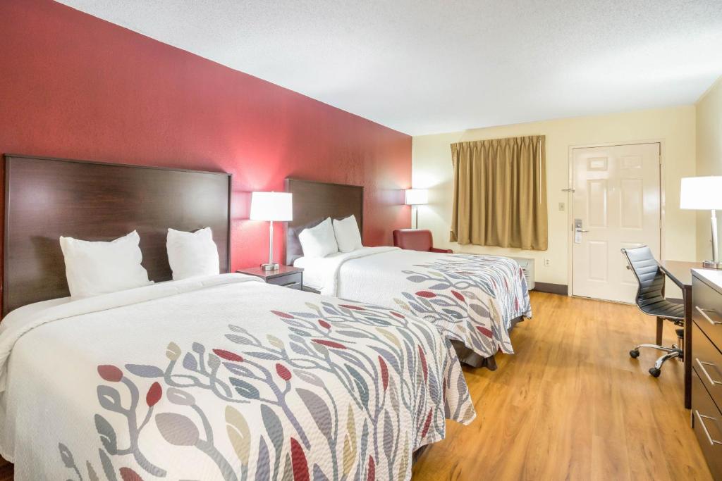 two beds in a hotel room with red walls at Red Roof Inn Clarksville in Clarksville