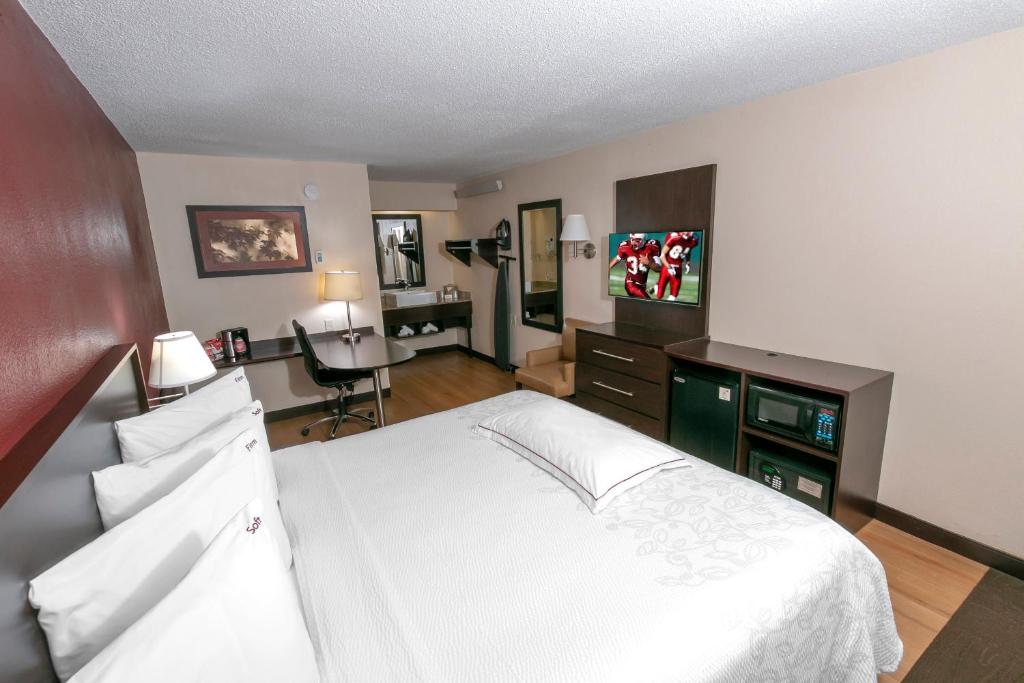 1 dormitorio con cama blanca y escritorio en Red Roof Inn PLUS+ Statesville, en Statesville