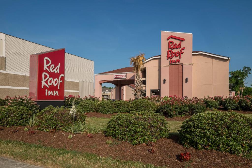 a building with red roof inn signs and bushes at Red Roof Inn Virginia Beach-Norfolk Airport in Virginia Beach
