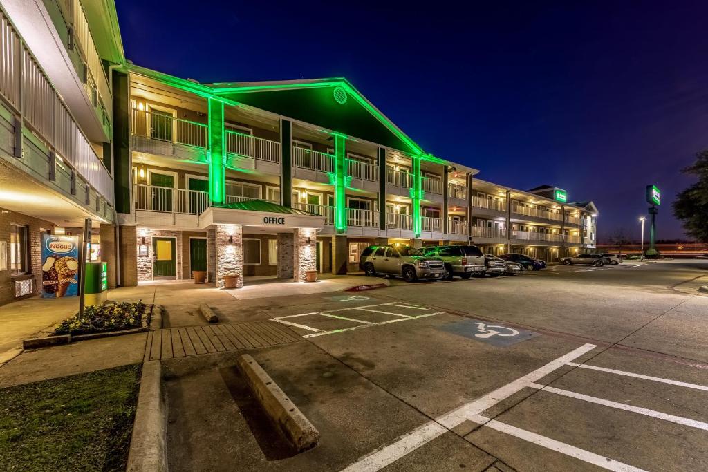 a large building with green lighting in a parking lot at HomeTowne Studios by Red Roof Dallas - Mesquite in Mesquite