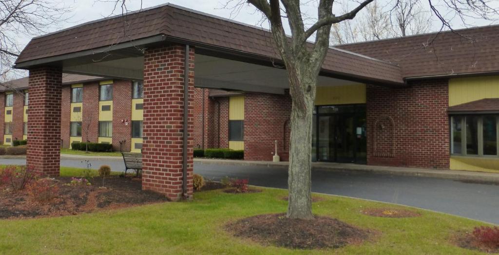 un edificio de ladrillo con un árbol delante de él en Red Roof Inn Fulton, en Fulton