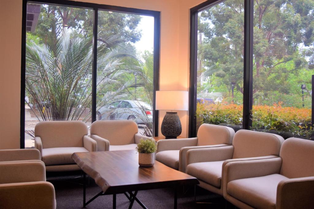 a waiting room with chairs and a table and large windows at ibis Thornleigh in Thornleigh