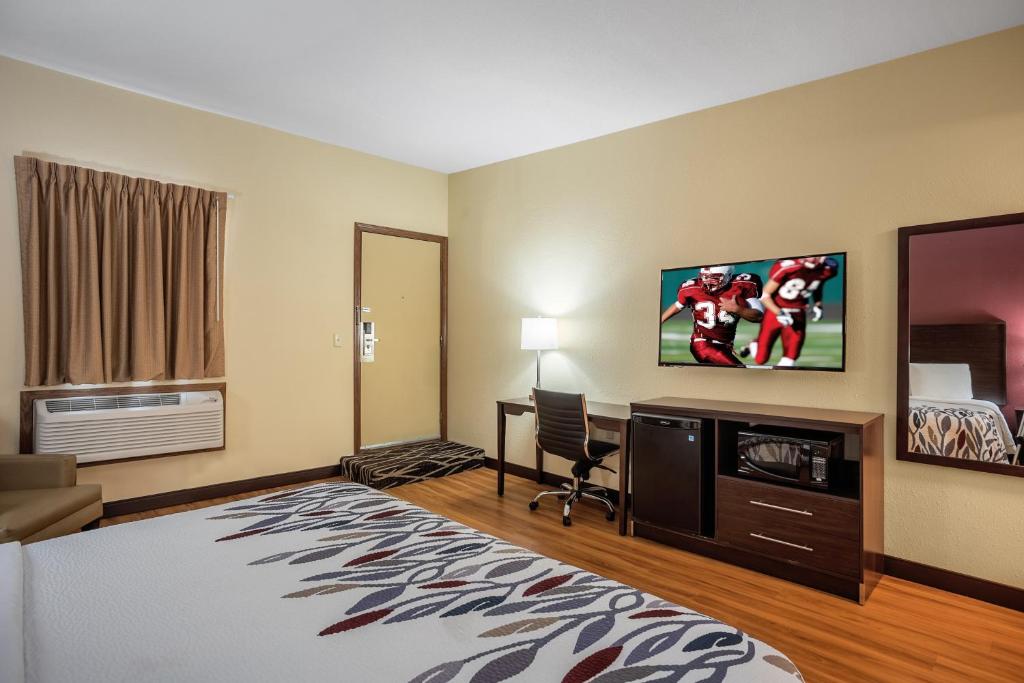 a hotel room with a large bed and a tv at Red Roof Inn Des Moines in Des Moines