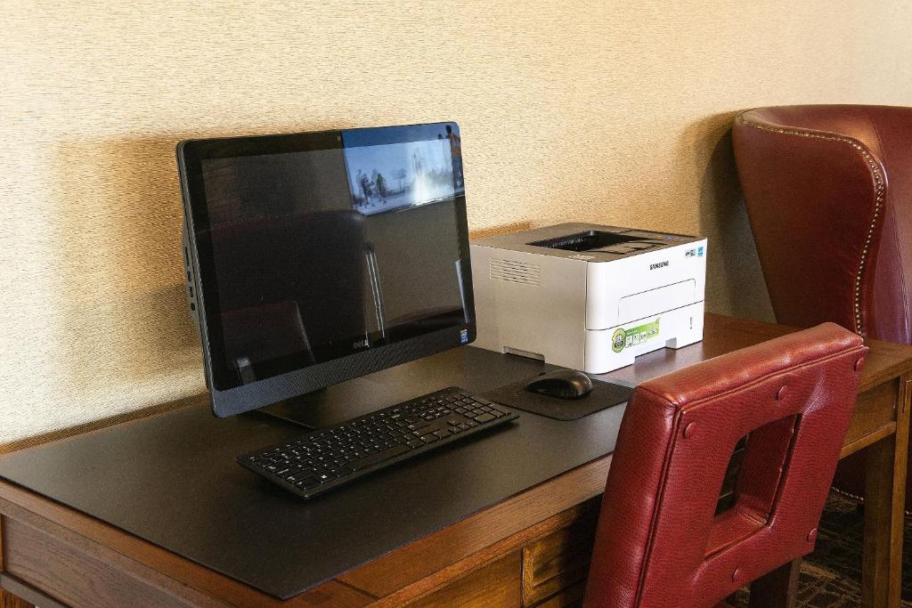 a computer monitor sitting on a desk with a printer at Red Roof Inn & Suites Omaha - Council Bluffs in Council Bluffs