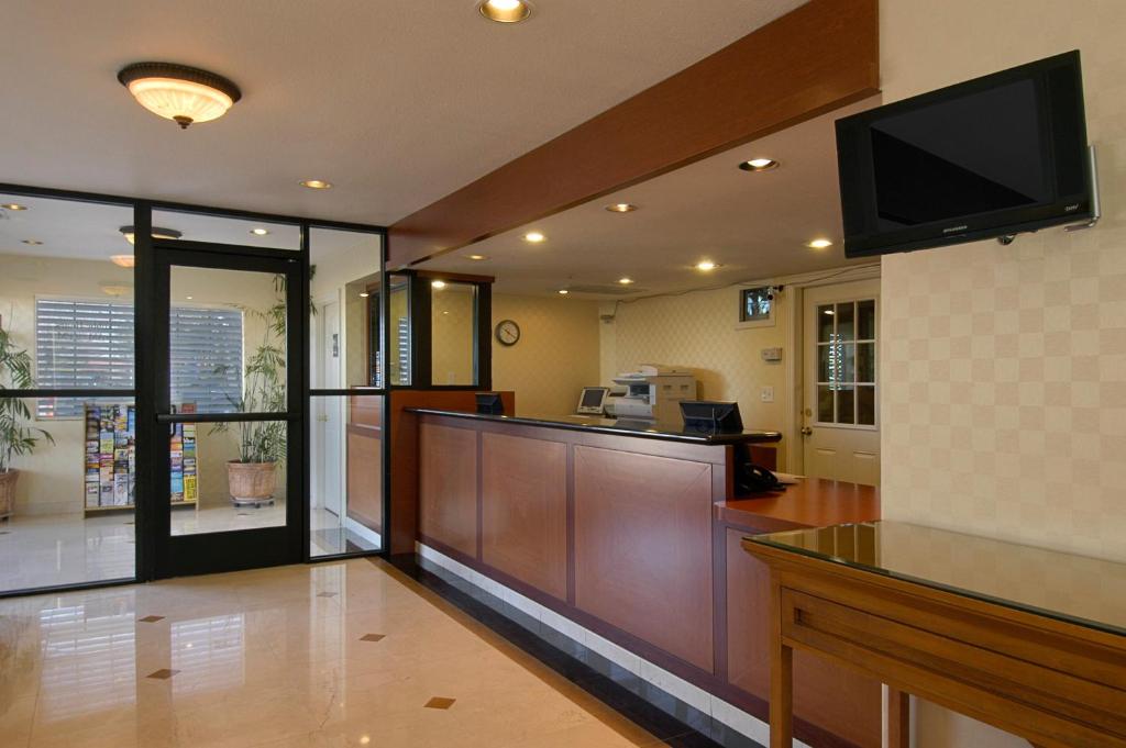 a lobby with a reception desk and a television at Mariposa Inn in Victorville