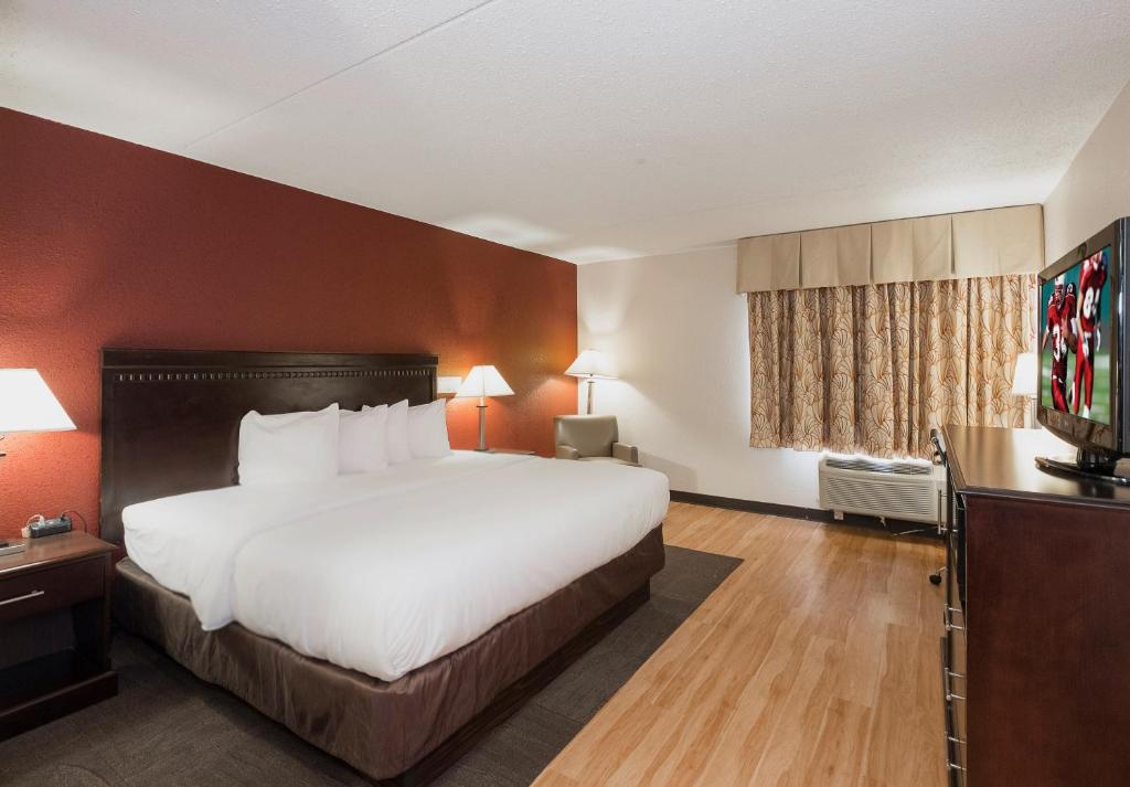 a hotel room with a bed and a flat screen tv at Red Roof Inn & Suites Mt Holly - McGuire AFB in Westampton Township