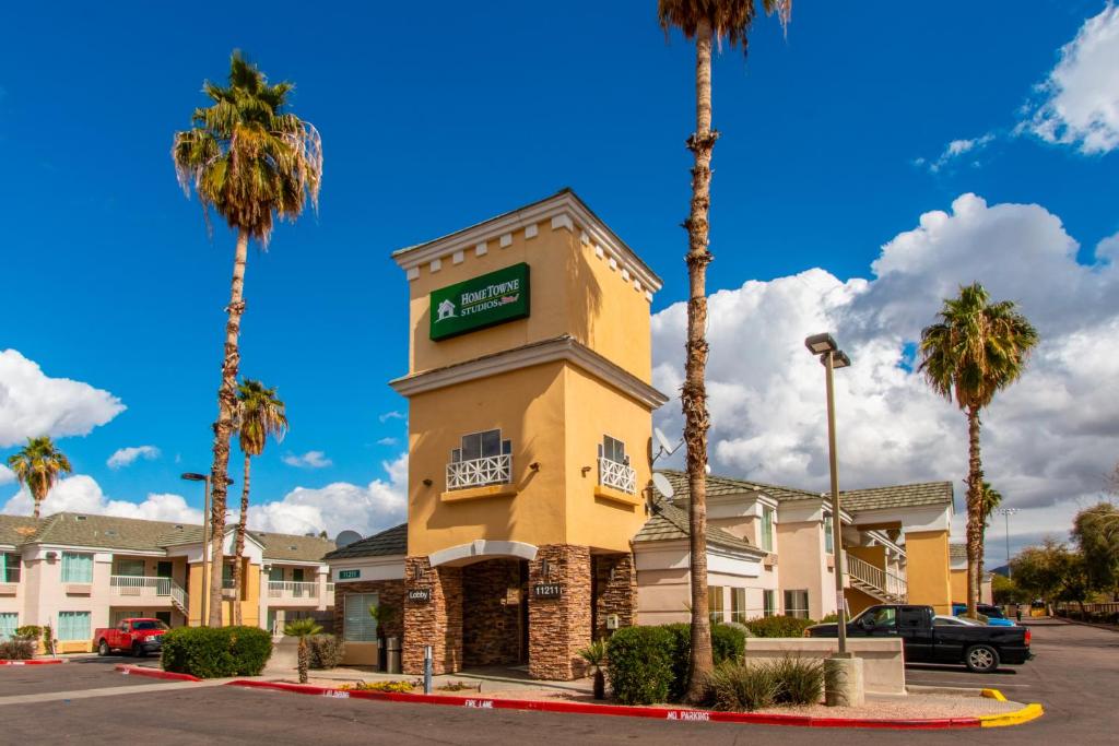 a hotel with palm trees in front of a building at HomeTowne Studios by Red Roof Phoenix - Black Canyon Highway in Phoenix