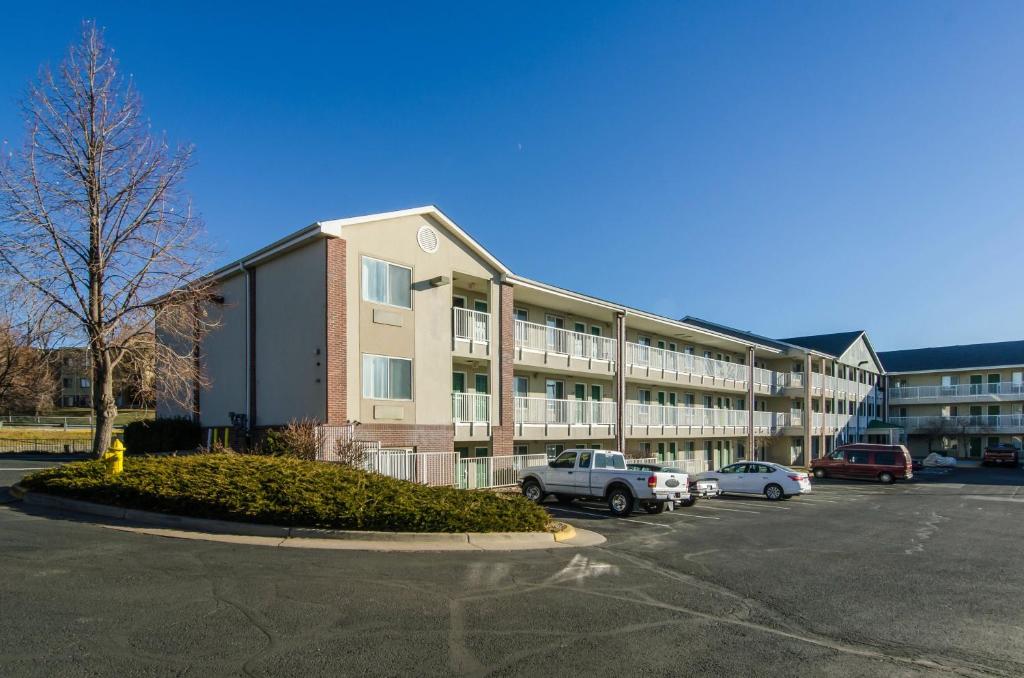 un gran edificio con coches estacionados en un estacionamiento en HomeTowne Studios by Red Roof Denver - Thornton, en Thornton