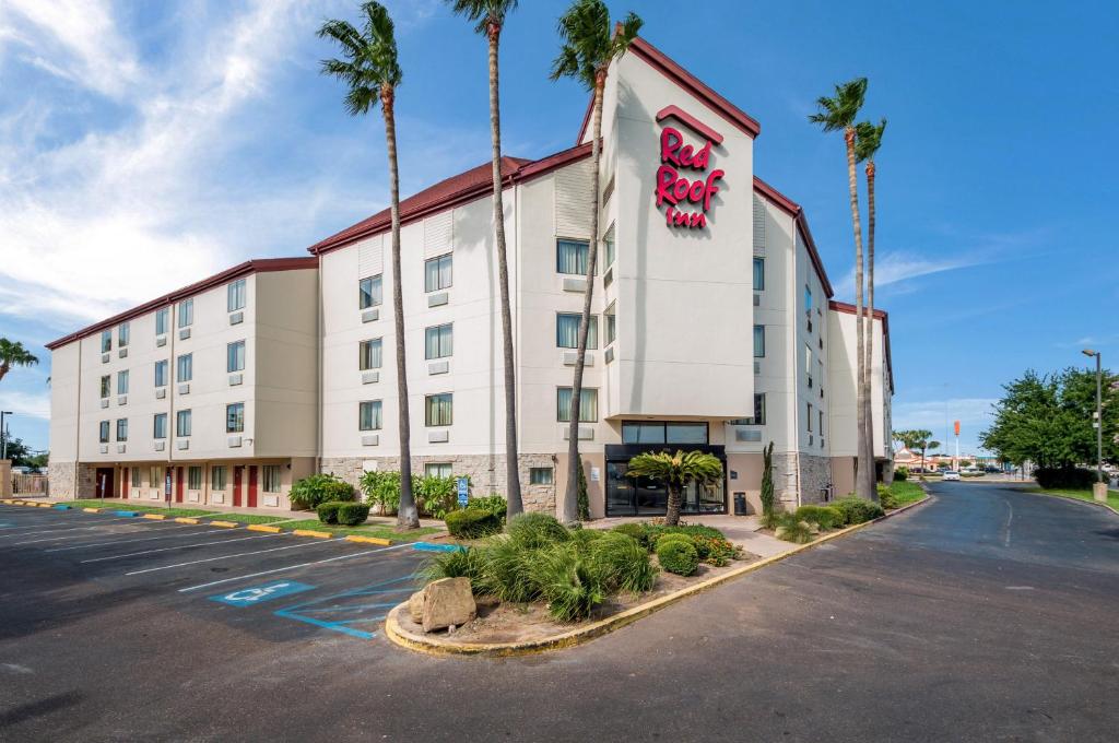 un bâtiment d'hôtel avec des palmiers dans un parking dans l'établissement Red Roof Inn Laredo, à Laredo