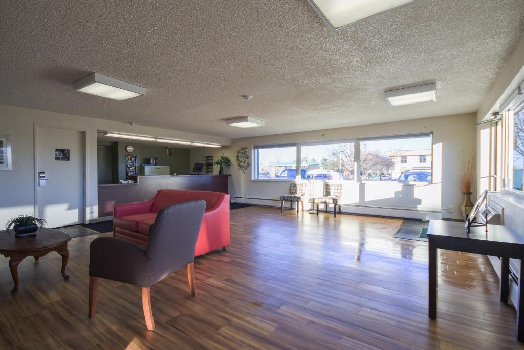 a living room with a red couch and a table at HomeTowne Studios by Red Roof Denver - Lakewood West in Lakewood
