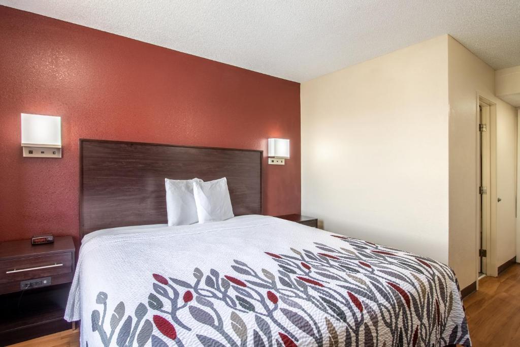 a bed in a hotel room with a red wall at Red Roof Inn El Paso West in El Paso