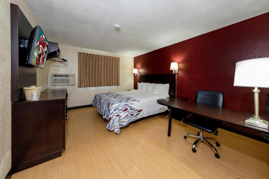 a hotel room with a bed and a desk at Red Roof Inn Jacksonville - Cruise Port in Jacksonville