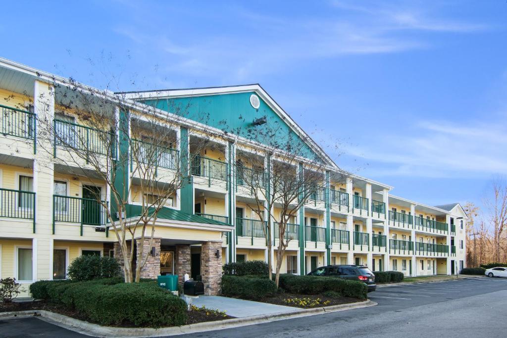 an apartment building with a green and white at HomeTowne Studios by Red Roof Raleigh – Durham in Durham