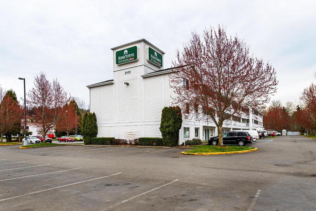 um edifício branco com uma torre de relógio num parque de estacionamento em HomeTowne Studios by Red Roof Tacoma - Puyallup em Puyallup