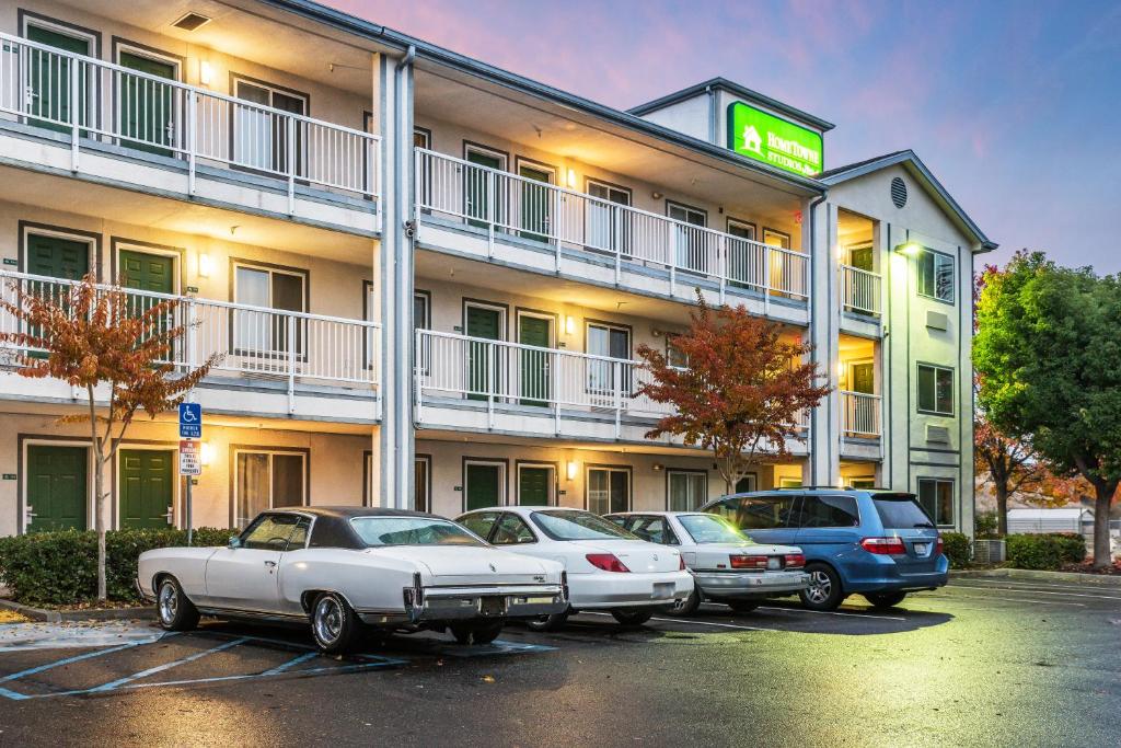 un hotel con coches estacionados en un estacionamiento en HomeTowne Studios by Red Roof Rancho Cordova, en Rancho Cordova