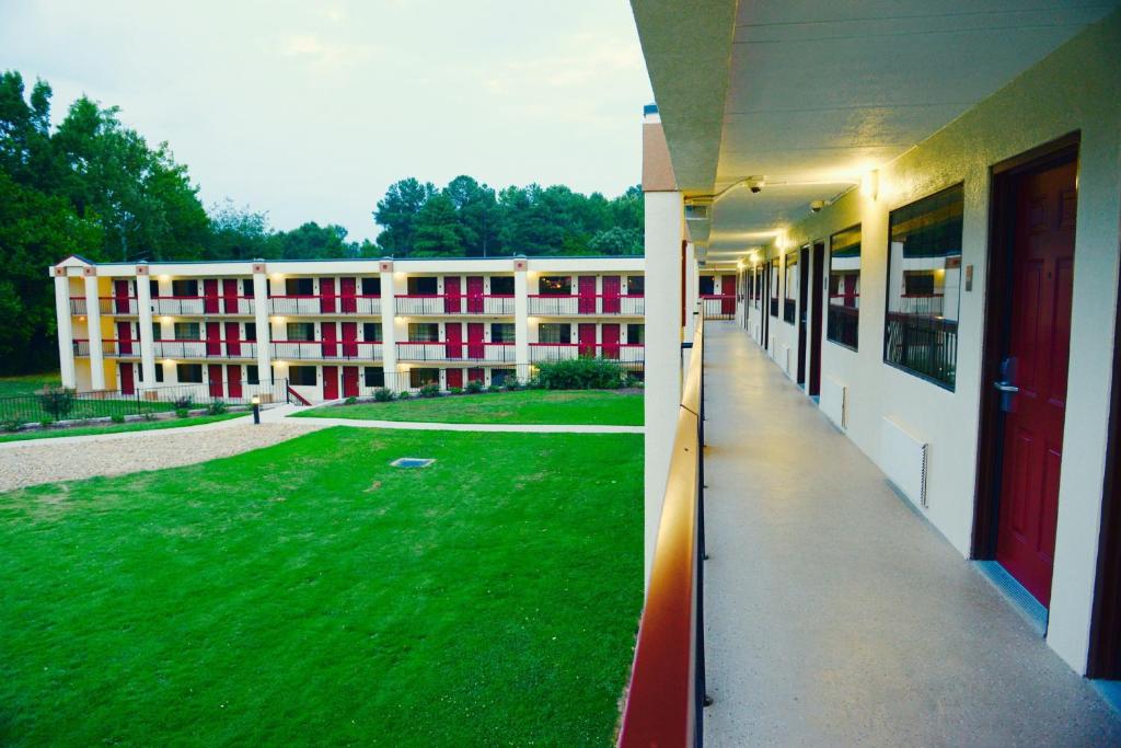 a large building with a green lawn in front of it at Red Roof Inn & Suites Commerce - Athens in Commerce