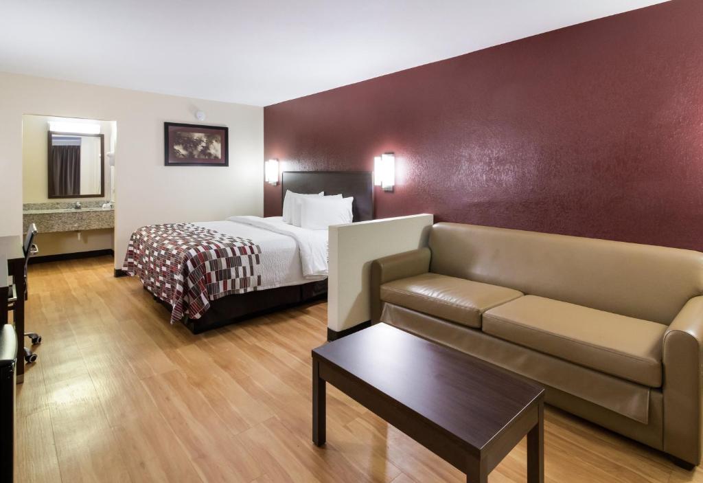 a hotel room with a bed and a couch at Red Roof Inn & Suites Commerce - Athens in Commerce