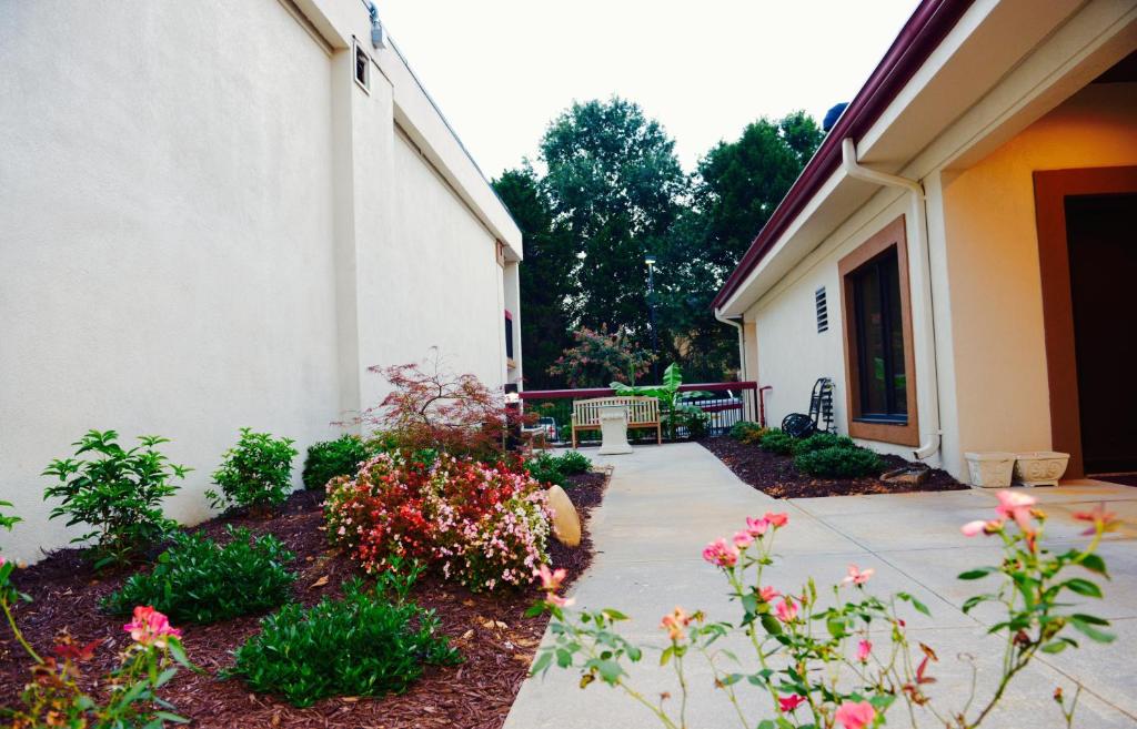 a walkway in front of a building with flowers at Red Roof Inn & Suites Commerce - Athens in Commerce