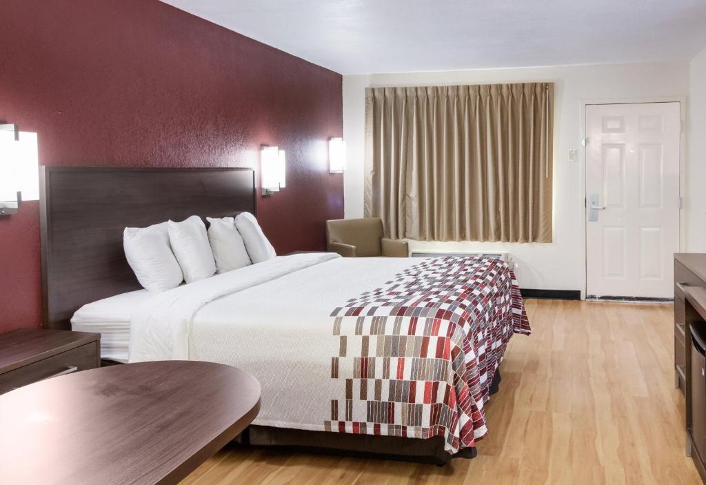 a hotel room with a large bed and a table at Red Roof Inn & Suites Commerce - Athens in Commerce