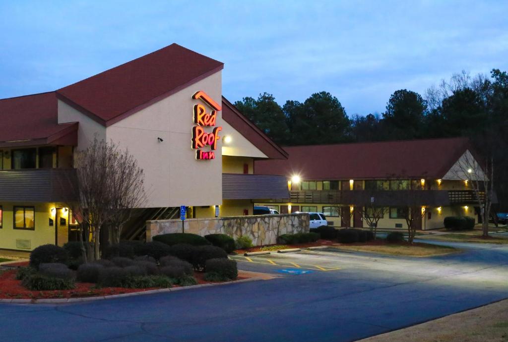 a hotel with a neon sign in a parking lot at Red Roof Inn Greenville in Greenville