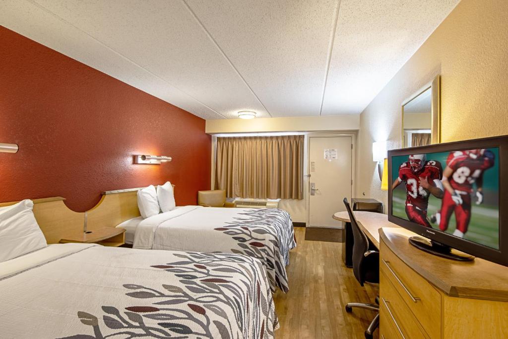 a hotel room with two beds and a flat screen tv at Red Roof Inn Johnson City in Johnson City