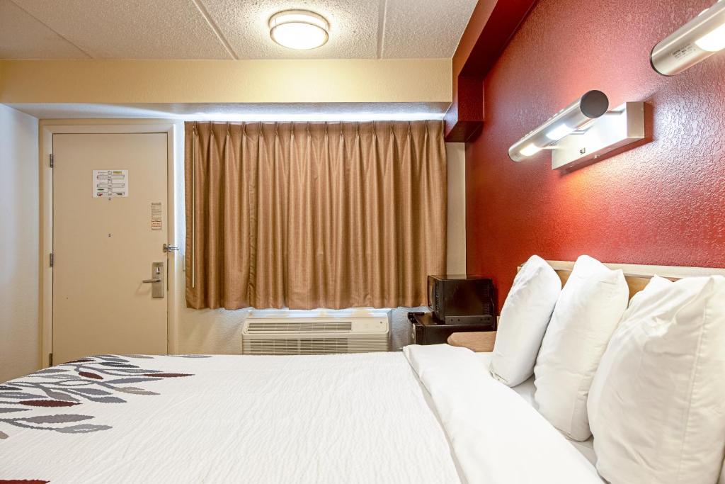 a hotel room with a large bed with white pillows at Red Roof Inn Johnson City in Johnson City